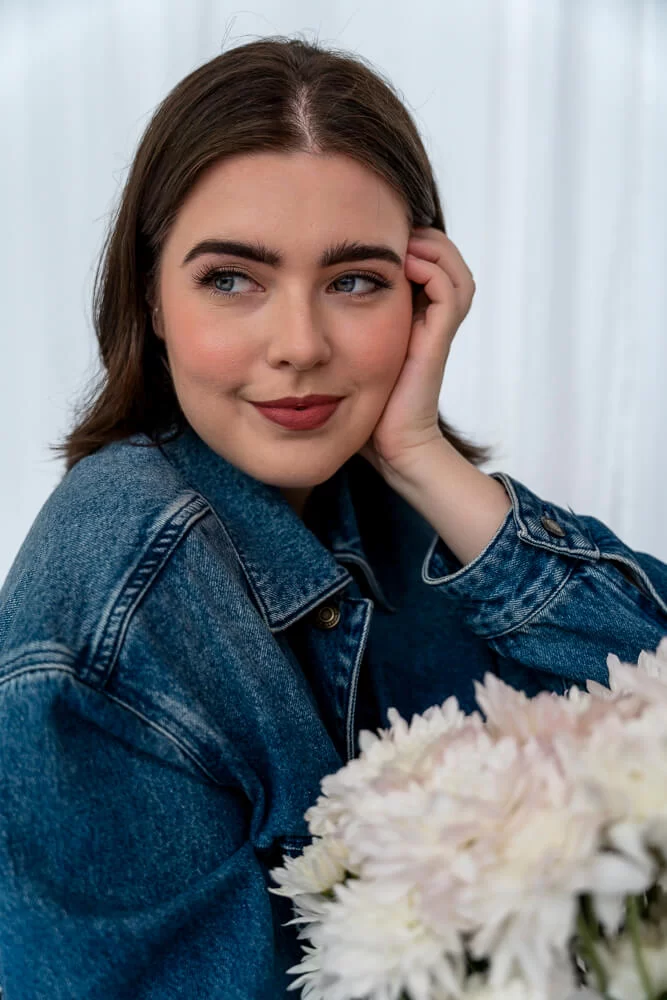 Gold Coast model with natural makeup, denim jacket, and white flowers